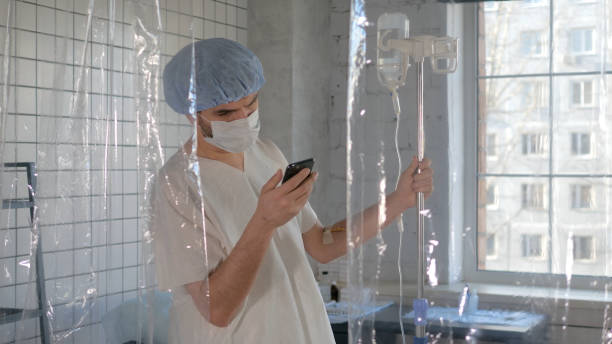 istock Young man patient with a medical face mask using phone in a hospital on a quarantine 1216106897