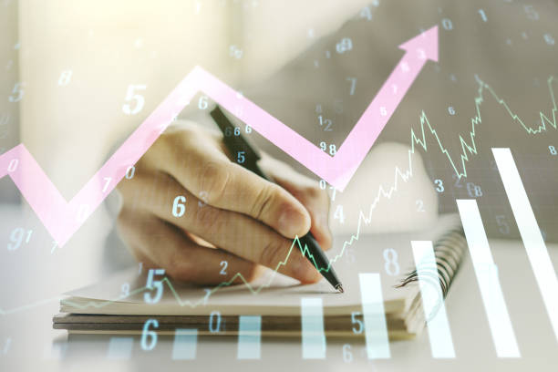 istock Multi exposure of abstract creative financial graph with upward arrow and man hand writing in notebook on background, forex and investment concept 1216107145