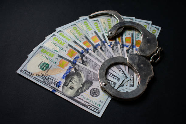 istock Fanned out dollar bills and handcuffs 1216110077