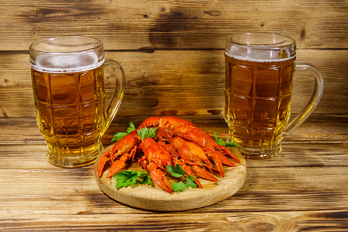 Boiled crayfish and two mugs of beer on a wooden table