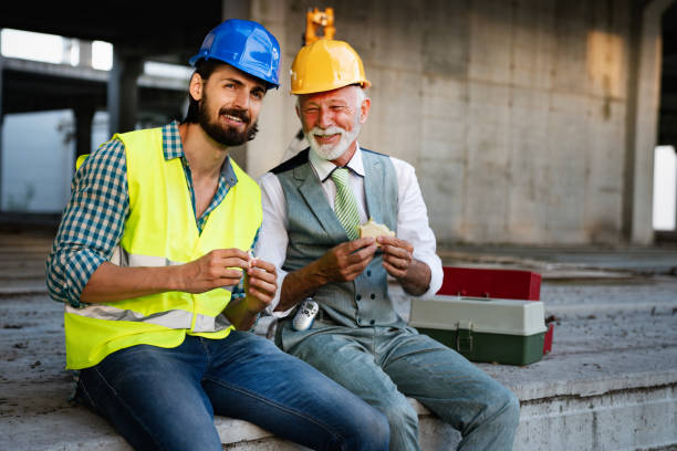 istock Happy mature and young engineer, architect, worker sitting at building site and resting 1216116878
