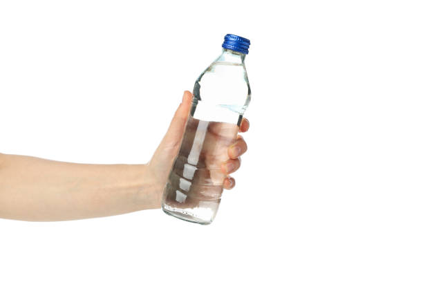 istock Female hand holds bottle with water, isolated on white background 1216117895