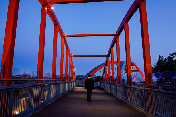 Stockholm, Sweden, March 29, 2020 A man walks alone on a red pedestrian and bicycle bridge the suburb of Vastberga.