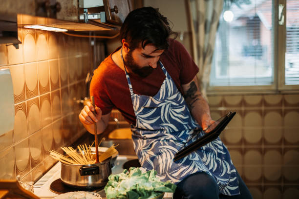 istock Man reading recipe on digital tablet and preparing spaghetti 1216123841