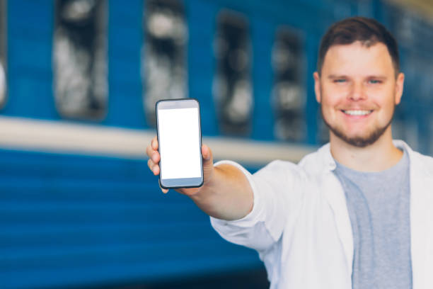 istock man holding phone with white screen at railway station train on background 1216124522