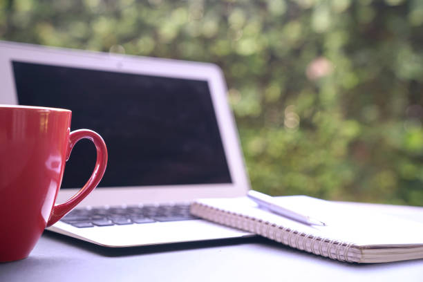 istock Red coffee cup with computer laptop and notepad at the background 1216124665