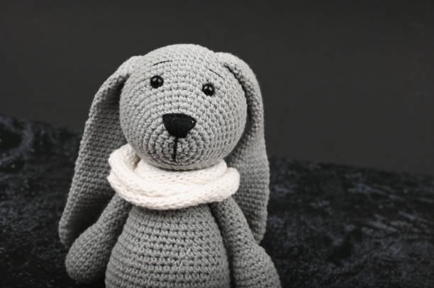 Gray knitted hare on a dark background. Black easter concept. Black eggs. Easter for black people