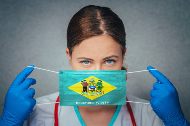 Coronavirus in U.S. State Delaware, Female Doctor Portrait, protect Face surgical medical mask with Delaware Flag. Illness, Virus Covid-19 in Delaware Coronavirus in U.S. State Delaware, Female Doctor Portrait, protect Face surgical medical mask with Delaware Flag. Illness, Virus Covid-19 in Delaware delaware us state stock pictures, royalty-free photos & images