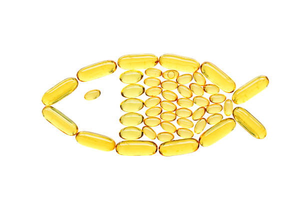 Transparent yellow medical capsules in fish shape, isolated on white background. Top view, health and care concept stock photo