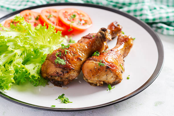 istock Grilled chicken legs with spices and fresh vegetables. Baked drumsticks. 1216128986