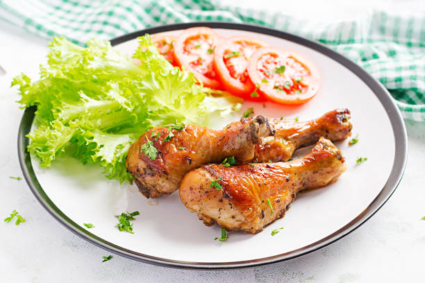 istock Grilled chicken legs with spices and fresh vegetables. Baked drumsticks. 1216129018