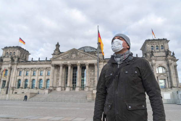 Posing in front of the Berlin Reichstag during the city's lockdown Adult man wearing a medical protective mask on his face posing alone outside the Berlin Reichstag building during the city's lockdown bundestag photos stock pictures, royalty-free photos & images