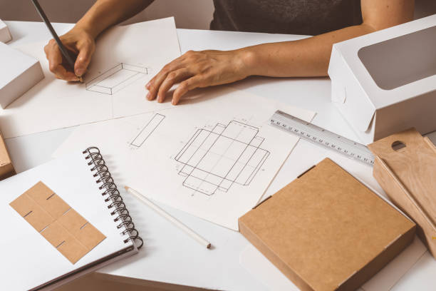 istock Hands designer draws a sketch of paper packaging. Creative development of ecological boxes. 1216129728