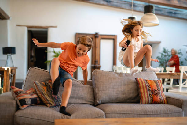 istock Fun-Loving 11 Year Olds Running and Jumping onto Sofa 1216129975