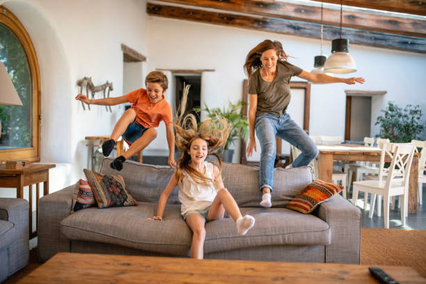 istock Active Mother and Young Children Jumping Over Back of Sofa 1216129989