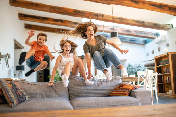 istock Energetic Mother and Young Children Jumping Over Sofa 1216129996