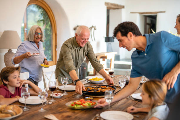 istock Smiling Senior Man Delivering Paella Pan to Dining Table 1216130025