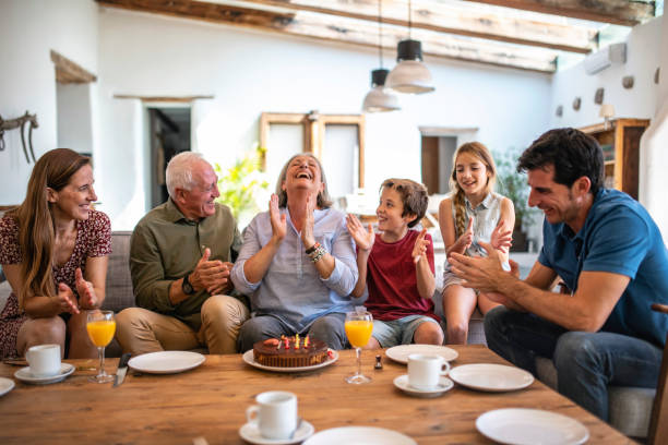 istock Lighthearted Senior Woman Claps After Blowing Out Candles 1216130054