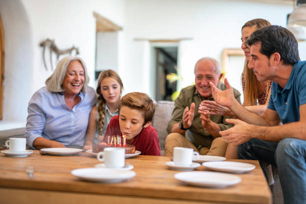 istock Grandparents and Father Watching as Boy Blows Out Candles 1216130084