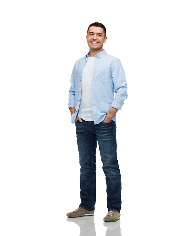 happiness and people concept - smiling man wearing shirt and jeans with hands in pockets