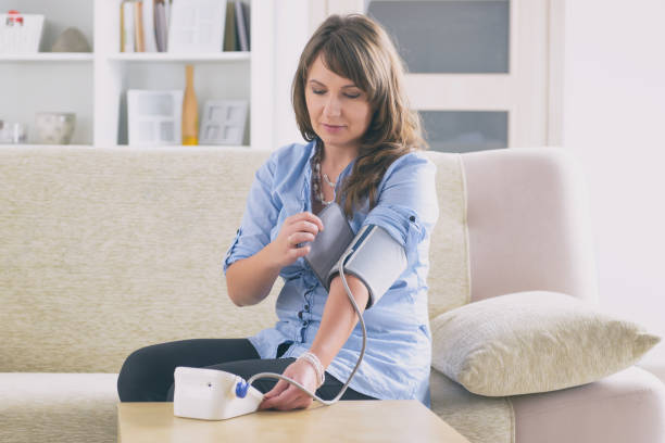 Checking blood pressure at home Women checking blood pressure at home hypertensive photos stock pictures, royalty-free photos & images