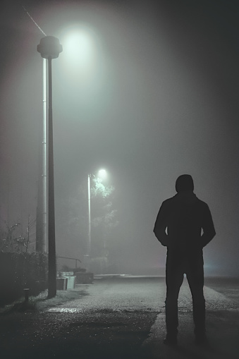 A creepy man standing in the dark streets of a city