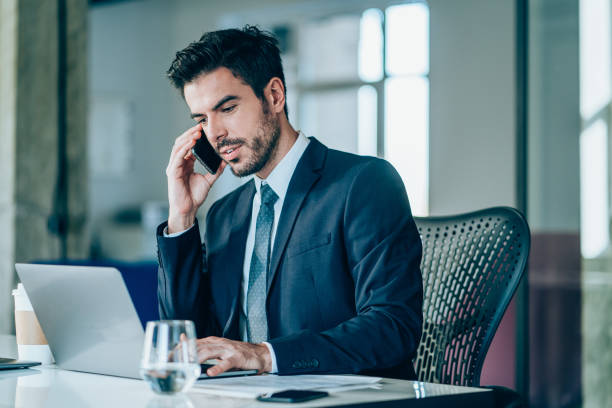Businessman working on laptop and talking on cellphone.