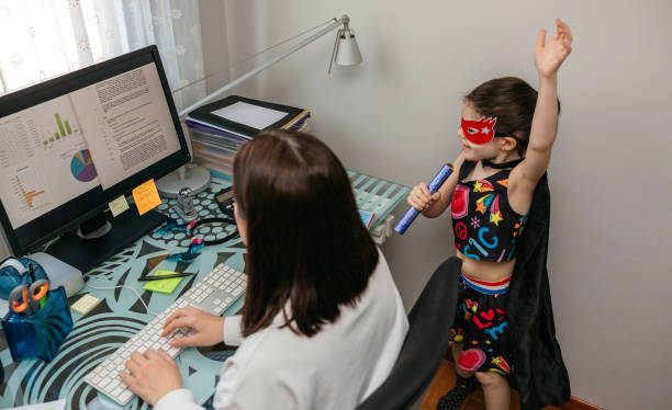 Woman working from home with her daughter singing by her side Top view of woman working from home with her daughter singing and playing by her side. Selective focus on girl in background inconvenience photos stock pictures, royalty-free photos & images