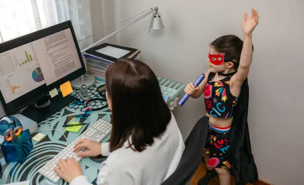 Photo of Woman working from home with her daughter singing by her side