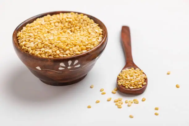 yellow moong mung dal lentil pulse bean in wooden and spoon bowl on white background ,