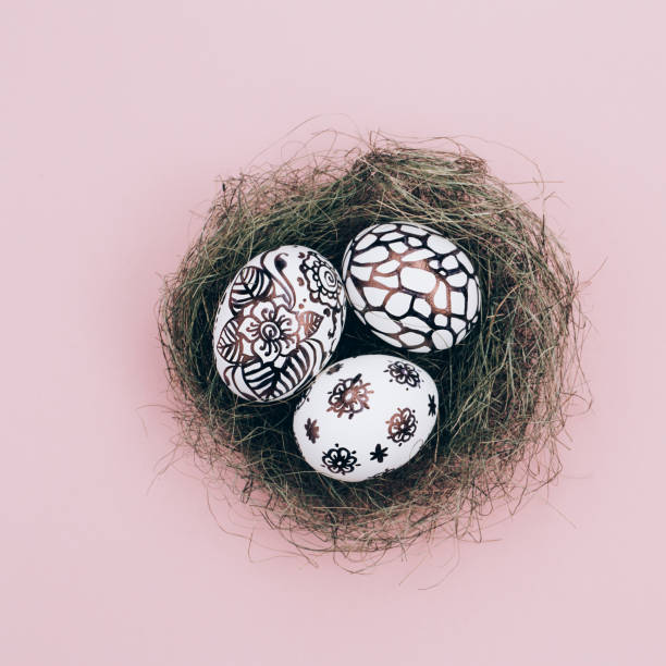 istock Three easter eggs are painted in black and white lie in a green nest 1216154763