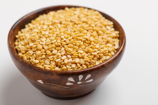 yellow moong mung dal lentil pulse bean in wooden bowl on white background ,