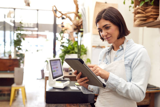 właścicielka z cyfrowym tabletem stojącym za biurem sprzedaży kwiaciarni - clothing store sales clerk usa clothing zdjęcia i obrazy z banku zdjęć