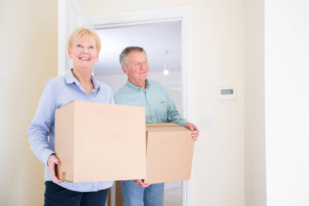 istock Senior Couple Downsizing In Retirement Carrying Boxes Into New Home On Moving Day 1216157533