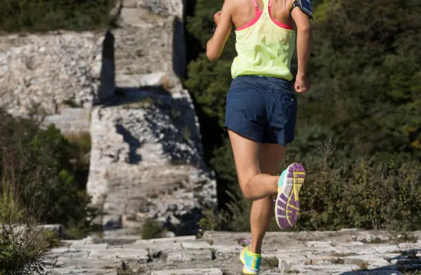 Photo of Young woman trail runner running on the great wall