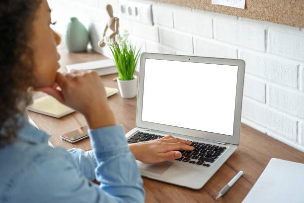 istock African girl student watching video course, distance e-learning, studying with online teacher by webcam. Remote education, work from home concept. Over shoulder close up laptop mock up screen view. 1216160042
