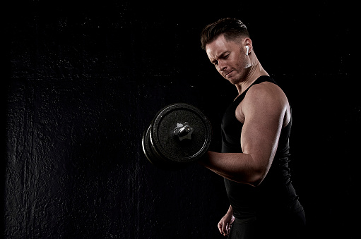 White young athletic man exercising with weights wearing ear pods