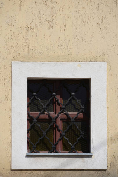 istock Old brown wooden window with yellow iron grid on yellow background 1216164619