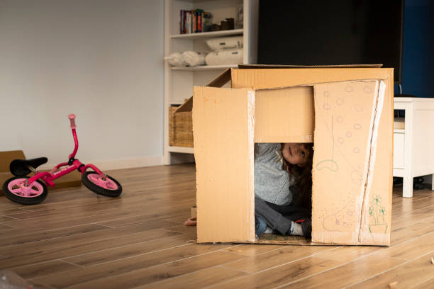 Little child girl playing in a cardboard playhouse stock photo