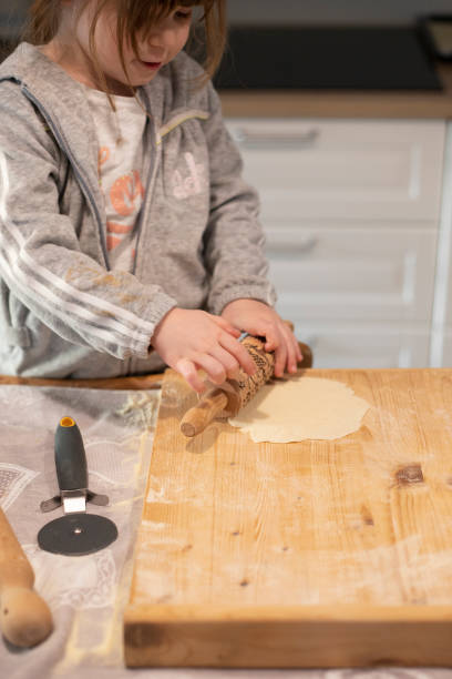 istock Child flattening pizza dough with rolling pin during lockdown. 1216166864