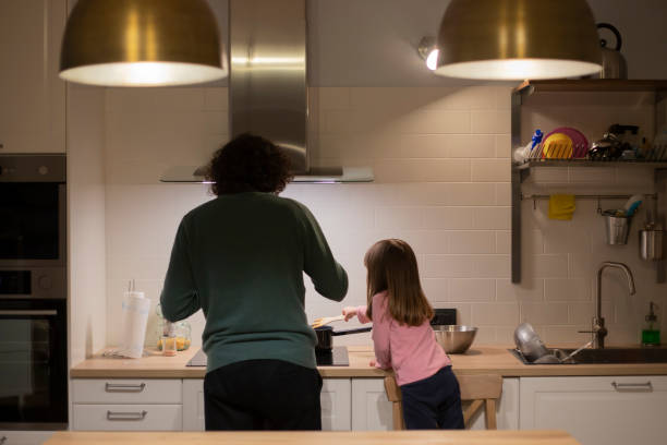 Father and little child girl cooking together during lockdown. stock photo