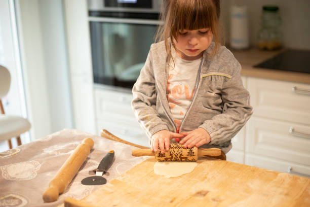 istock Child flattening pizza dough with rolling pin during lockdown. 1216166869