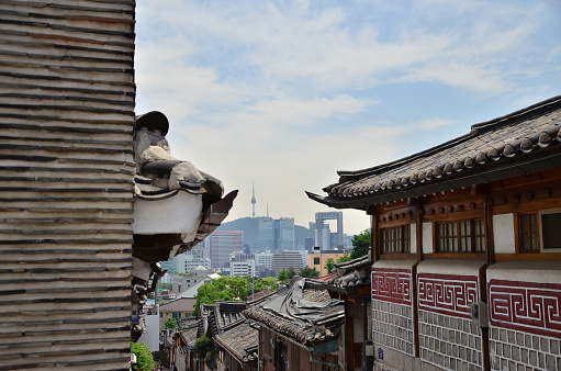 Bukchon Hanok Village is a Korean traditional village in Seoul. A contrast view between traditional village and city skyline.