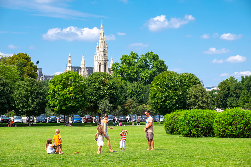 A family with young children plays in a garden next to the Hofburg, the Vienna Imperial Palace.