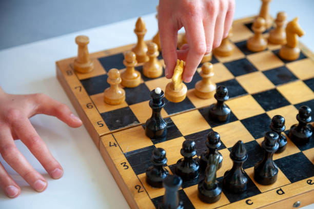 istock A child plays chess alone. Old wooden chessboard. Children's hands. Chess pieces on a chessboard 1216169207