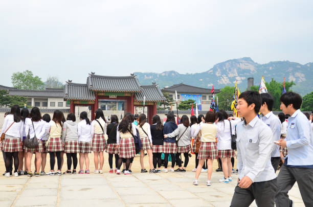 A group of high school student watching the gate opening ceremony at Gyeongbokgung Palace during hot summer day.