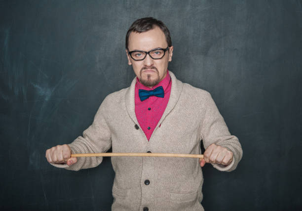 Angry teacher with pointer on blackboard stock photo
