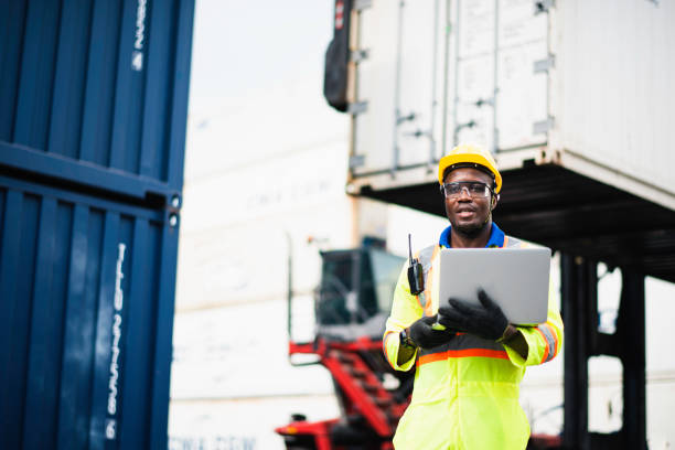 istock Adult African american men worker Check and control loading freight Containers by use computer laptop at commercial shipping dock felling serious. Cargo freight ship for import export concept 1216172915