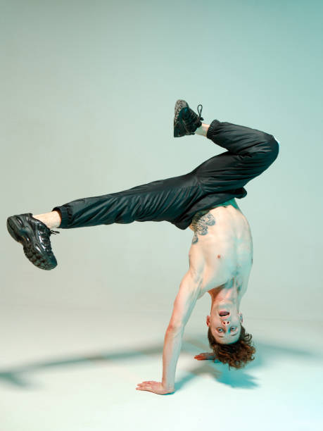 istock A young graceful guy is dancing a break dance on the floor without a t-shirt. Complex tricks. Body with tattoos. 1216173532