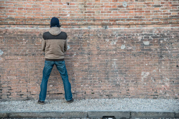 back man who is peeing on a wall stock photo